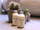 Two containers of all-natural leather balm next to a plant